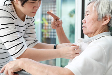 Fototapeta premium Angry asian senior grandmother scolding woman,Aggressive old elderly people shouting pointing finger at frightened female caregiver,dissatisfaction irritated,violence aggression,mental health concept