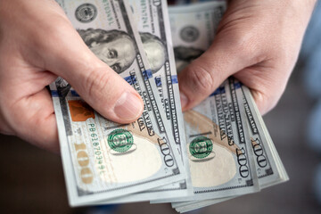 Close up male hand Counting and holding money us dollar. The concept of financial business and crisis.