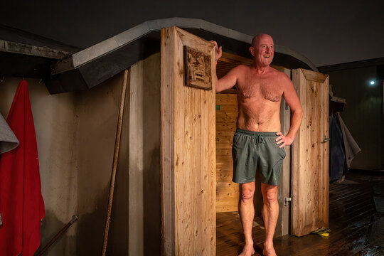 Copenhagen, Denmark A man stands outside a door leading to a warm sauna.