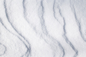 winter background with snowy ground. Wind sculpted patterns on snow surface.