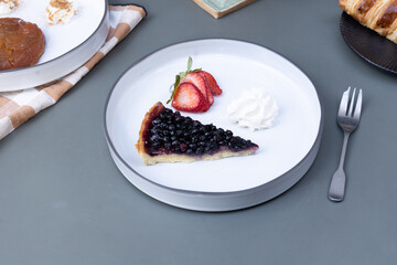 blueberry tarte with strawberries and cream on a plate