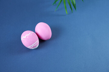 Easter pink eggs on a blue background with a green twig
