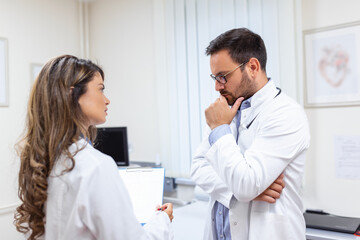 Two medic colleagues in white coats, holding clipboard. They are so successful, smile and work in team together