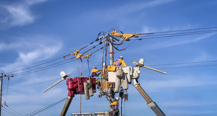 Electricians on crane working to fix power line