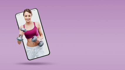 Smiling young sportswoman working out with dumbbells in a smartphone videocall and smiling, online  service concept