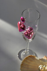 Pair of pink heart shaped earrings on the champagne glass with pearls in seashell isolated on white. Valentines Day.
