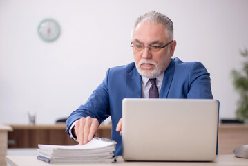 Old male employee working in the office