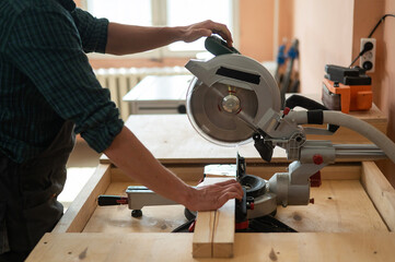 Master cuts the board with a circular saw in the workshop. 