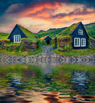 Typical Icelandic turf-top houses reflected in the calm waters of calm water river. Incredible summer sunrise on Skogar village. Fantastic outdoor scene of Iceland. Traveling concept background..