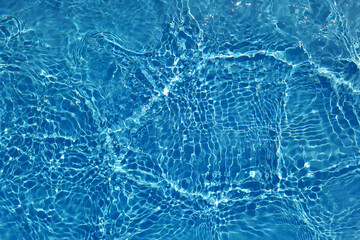 Defocus blurred transparent blue colored clear calm water surface texture with splashes and bubbles. Trendy abstract nature background. Water waves in sunlight with copy space. Blue water shine