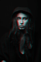 Beautiful woman studio portrait in red and blue color split effect. Model with dreadlocks hiding under hood and looking to camera with seductive look. Futuristic looking style