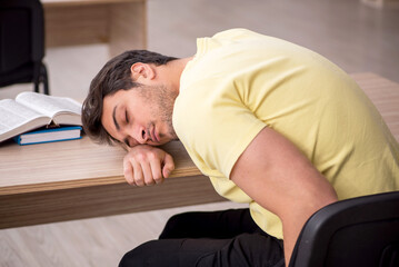 Young male student teacher sitting in the classroom
