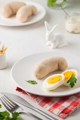 Polish Easter breakfast, white sausage and boiled egg on a white plate on a light concrete background. Served with white horseradish.