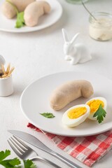 Polish Easter breakfast, white sausage and boiled egg on a white plate on a light concrete background. Served with white horseradish.