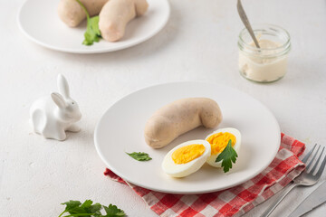 Polish Easter breakfast, white sausage and boiled egg on a white plate on a light concrete background. Served with white horseradish.