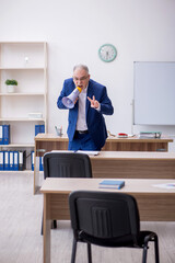 Old male teacher holding megaphone in the classroom