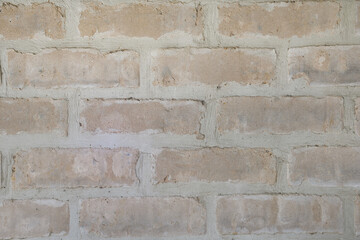 Close-up warm pinkish coloured coarse rustic sandstone house bricks with vertical and horizontal joint lines