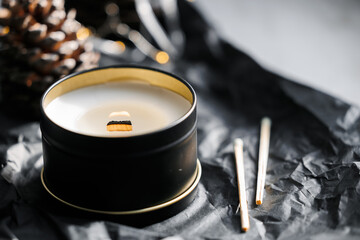 Soy scented candles in metal tins, boxes. Candles on the table in the room with a backdrop of pinecone and Christmas lights.  Modern handmade coconut wax candles without paraffin. burns Wooden wick. 