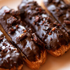 Eclairs with chocolate glaze and nuts. French dessert. Custard cake with cream. Sweet pastry. Big plan. Soft focus. View from above. High quality photo