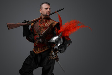 Shot of isolated on gray background musketeer with rifle and plumed helmet.