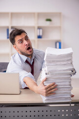 Obraz premium Young male employee unhappy with excessive work in the office