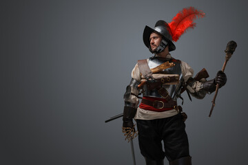 Portrait of medieval musketeer man with plate armor and torch isolated on grey.