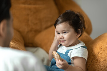 Cute little toddler holding toy while sitting on floor with stuff toy playing with father at home