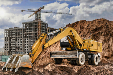 A large yellow excavator moving stone or soil in a quarry. Heavy construction hydraulic equipment. Excavation.