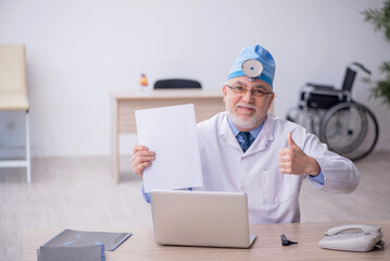 Old male docror otolaryngologist working in the clinic