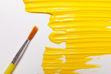 Paint brush and yellow paint on white background