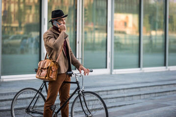 Obraz premium Young handsome man with casual clothes driving bicycle in the city - Student with stylish retro vintage clothing ride on a bike, concepts about business, green mobility, alternative transportation