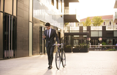 Young handsome man with business suit driving bicicyle to go to office - Corporate businessman portrait biking in the city, concepts about business, green mobility and lifestyle