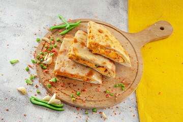 Stuffed chicken naan moroccan flavour with spices and veggies on a wooden circular plank.