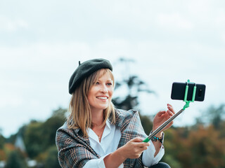 Caucasian girl with French hat takes pictures of herself with a selfie stick