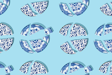 Pattern with broken china porcelain plates on blue background. Minimal concept. Flat lay.