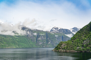 Beautiful landscape with snowy mountain peaks and waterfalls in Geiranger fjord, Norway