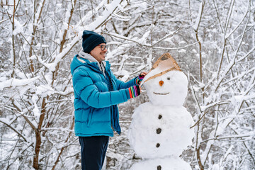 Man building a snowman in winter forest
