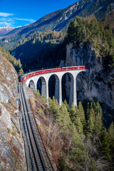 A train going through a tunnel onto a bridge.in the mountains Landwasser viaduct
