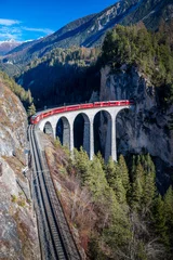 Wall murals Landwasser Viaduct A train going through a tunnel onto a bridge.in the mountains Landwasser viaduct