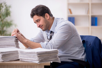 Fototapeta premium Young male employee and too much work in the office