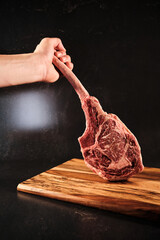 Toma hawk raw beef, hand holding