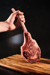 Tomahawk raw beef, hand holding