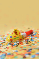 Carnival party paper whistle on colorful confetti background