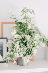 Bouquet of fresh white jasmine flowers in vase as home decoration. Indoor arrangement of branches from flowering shrub in springtime. Garden flowers decor.