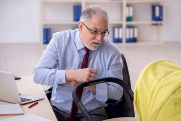 Old male employee looking after new born at workplace