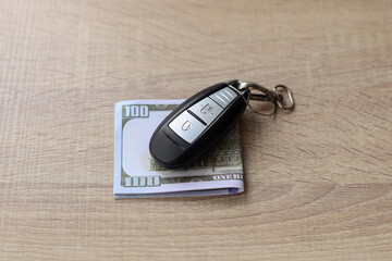 Car key and us dollar on wooden table. Finance and insurance concept. 