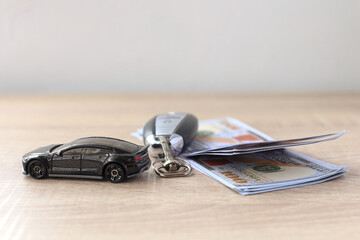 Black car, key and us dollar on wooden table. Finance and insurance concept. 