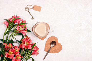 Obraz na płótnie Canvas Bouquet of Alstroemeria flowers, cup of coffee, and key with tag on a white marble background.