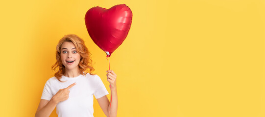 amazed redhead lady pointing finger on romantic gift of party balloon. happy valentines day....