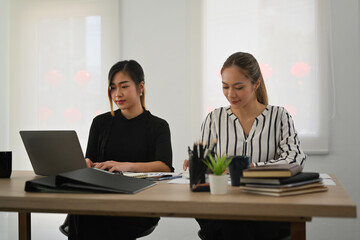 Two focused female employee preparing presentation for company clients or investors at office
